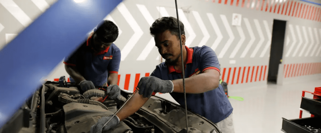 A pair of Petromin Express employees working on a vehicle's engine.