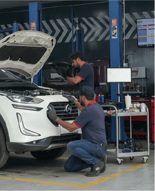 A pair of Petromin Express employees working on a car's front with the bonnet open.