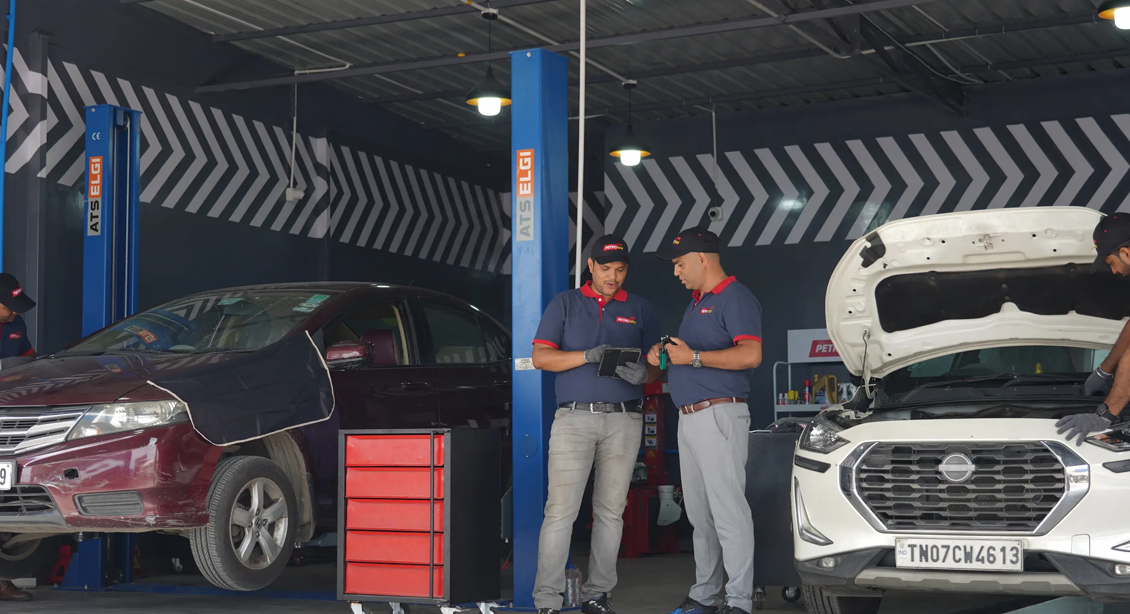 Two employees of Petromin Express sharing a device while working in a service centre.
