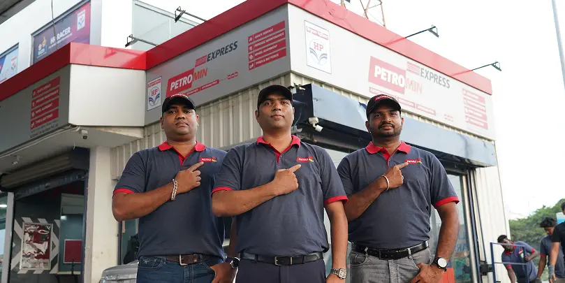 Three of Petromin Express's employees standing in front of a service centre.